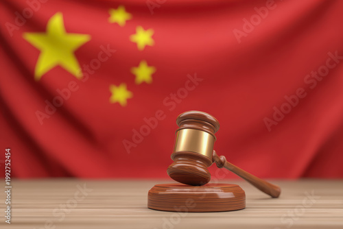 A wooden and gold-banded judge's gavel resting on a sound block on a light wooden surface, with a blurred Chinese national flag filling the background.