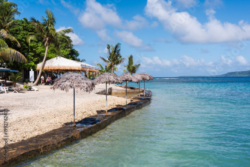 Fotografi Coral beach with umbrellas on Hideaway Island in the South Pacific