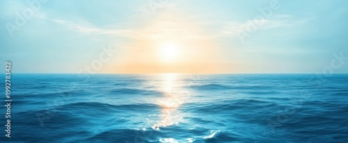 serene sunrise over a calm blue ocean with gentle waves and a shimmering sun reflection on the horizon