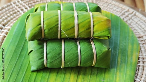 Khao Tom Mud or banana in sticky rice in fresh green banana leaf before cooking, popular dessert recipe in Thailand.