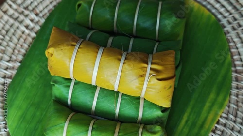 Khao Tom Mud or banana in sticky rice in fresh green banana leaf before cooking, popular dessert recipe in Thailand.