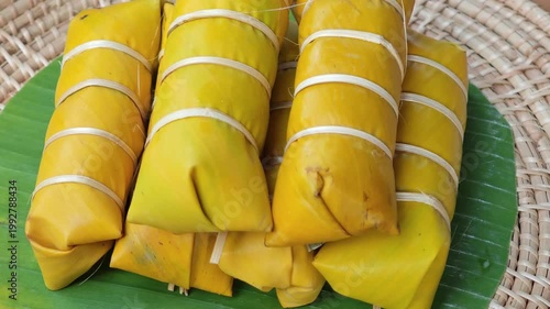 Khao Tom Mud or banana in sticky rice in fresh green banana leaf before cooking, popular dessert recipe in Thailand.