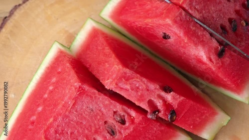 Female hands cutting fresh juicy watermelon slices on cutting board.
