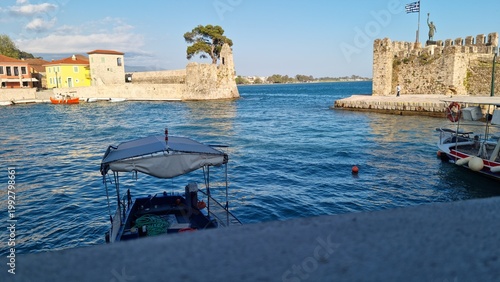 Nafpaktos with castle walls and Greek flag at sunset