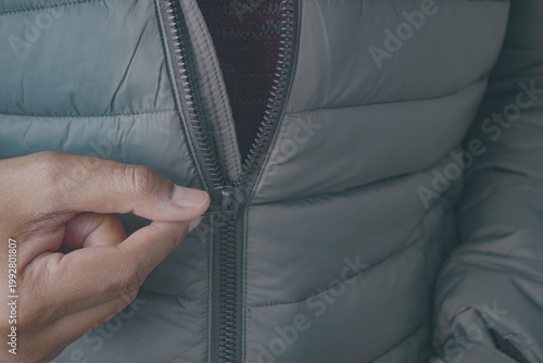 Tablou pe pânză Person zipping up a gray jacket outdoors in winter