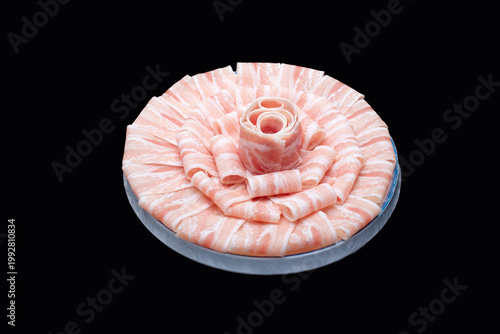 Foto Fresh marbled pork slices arranged like a flower on plate against black backgrou