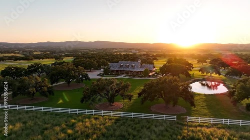 Aerial drone footage of a serene ranch estate at sunset with rolling hills and trees