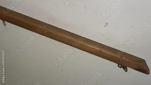 Wall mounted wooden handrail with metal support bracket along staircase showing interior structure and home safety detail