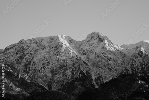 Snowy mountain peaks rise in the clear sky during the day in winter, showcasing the beauty of nature. Giewont, Zakopane, Poland. Black and white photo