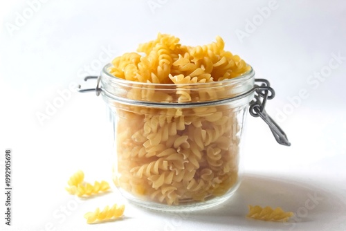 fusilli pasta in a glass jar isolated on a white background