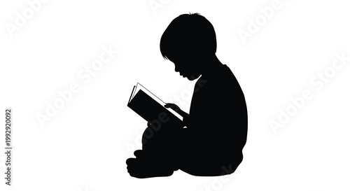 Silhouette of a child absorbed in reading a book seated on the floor