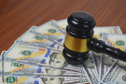 Gavel of justice and legal authority rests on scattered dollar bills, symbolizing financial power, court settlements, and economic law