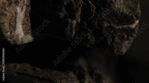Close-up dark rock layers with rough texture and deep shadows