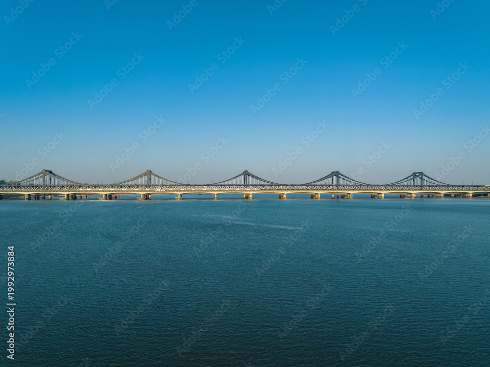 Fototapeta premium Hangzhou Qianjiang Second Bridge over calm river under blue sky