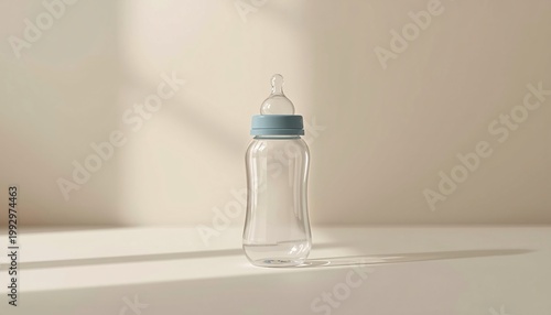 Clear glass baby bottle with blue ring and nipple filled with water, backlit with soft shadow