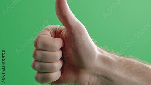 Male hand showing thumbs up gesture on green screen background.