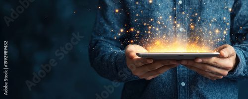  person holds a tablet emitting bright sparks and glowing light, symbolizing technology and innovation.