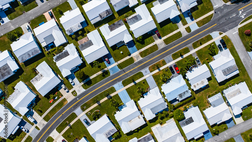 Aerial view of compact houses with white roofs, neatly aligned along streets with cars parked outside, a grid of modern suburban living, Florida, United States.