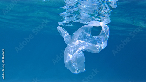 Obraz na plátně A plastic bag floats on the surface of clear blue water, contributing to plastic pollution
