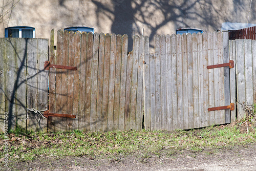 Photos An old, rickety gate made of old planks with rusty hinges.