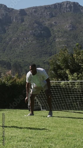 Vertical video: Lunging keeper in striped shirt as youth kicking ball into goal trying to score