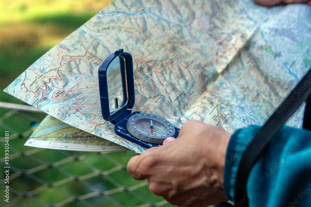 Fototapeta premium Senior hand holding compass and map navigating outdoor adventure
