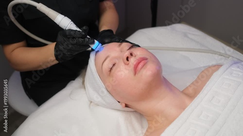Professional beautician performing a rejuvenating hydrafacial procedure on a client's face. Modern cosmetology for skin cleansing and anti-aging care