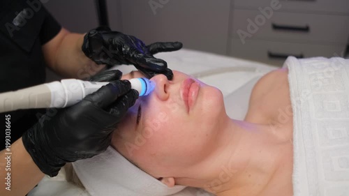 Professional beautician performing a rejuvenating hydrafacial procedure on a client's face. Modern cosmetology for skin cleansing and anti-aging care