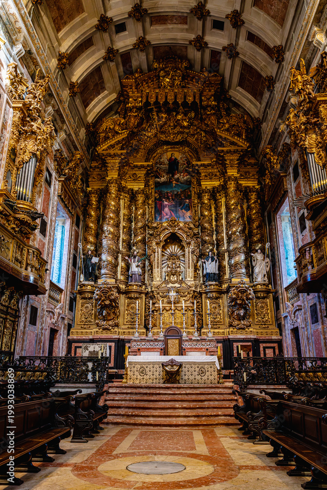 Obraz premium View inside Porto Cathedral showing central nave with stone arches wooden benches and ornate golden altar. Historic religious architecture with visitors sitting in quiet atmosphere.