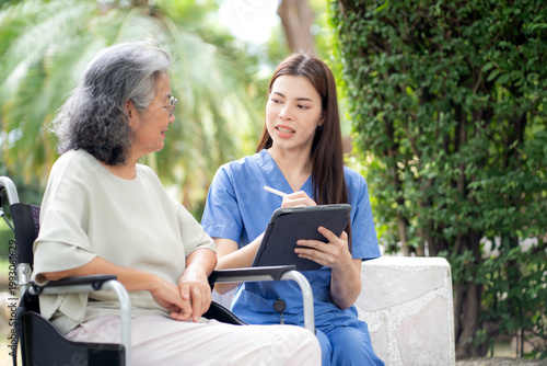 Female caregiver using digital tablet for senior patient consultation, professional nurse checking health record outdoors, elderly care assessment with checkup in park, health care support.