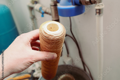 Dirty water filter cartridge being replaced in a home plumbing system