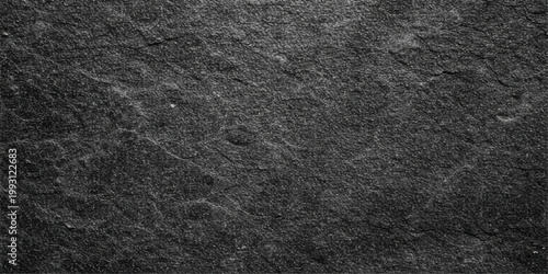 A closeup of a dark black leather and fabric material texture shows a rough grunge pattern on a gray stone surface backdrop