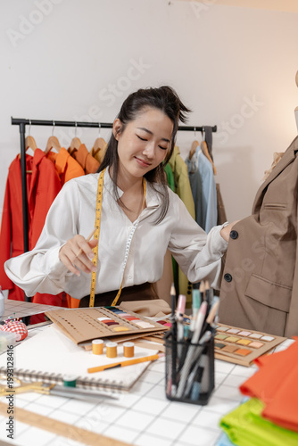 Fashion designer selecting colors and evaluating garment design on mannequin while developing clothing concepts and planning tailoring details in a professional fashion studio.