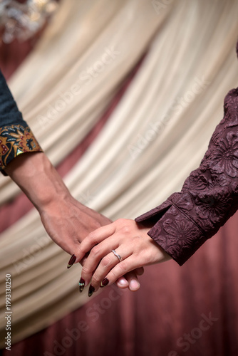 Softly draped curtains frame two hands joined