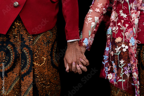 Red jackets with intricate batik patterns meet hands