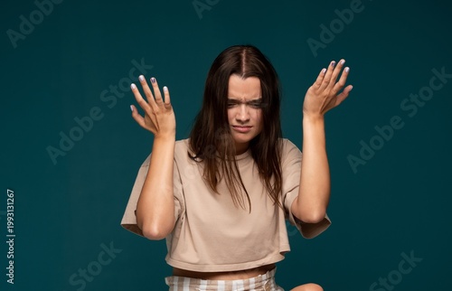 Schilderij op canvas Young woman shrugging her shoulders and raising hands in confusion, expressing f