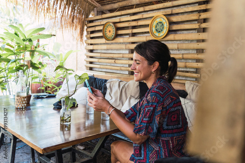 Woman enjoying a tropical cafe environment while connecting with her mobile phone