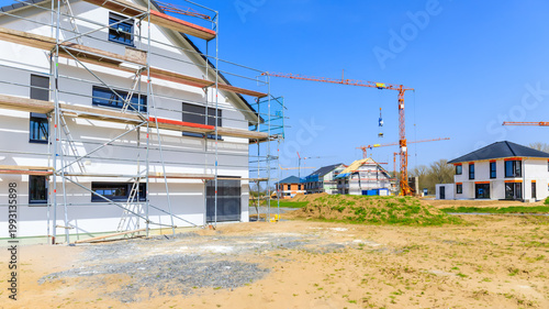 Construction site with new buildings and cranes in bright weather during day near residential area