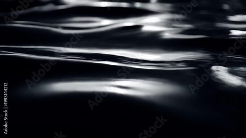 Smooth dark water surface with elegant monochromatic ripples and subtle light reflections