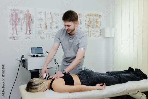 Physical therapist performing back shockwave therapy on woman