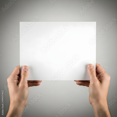 A pair of hands holding a blank white piece of paper against a dark background.