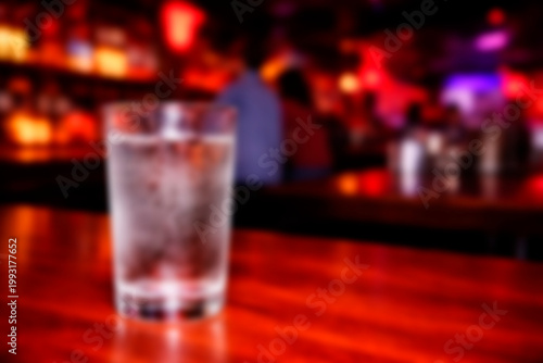 Glass of Water on Bar Counter in Nightlife Setting. Blurred background, copy space