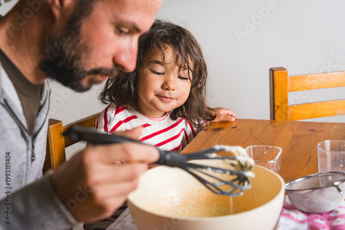father daughter baking together at home in the kitchen making dough, concept of fatherhood and bonding with children, cooking together with complicity