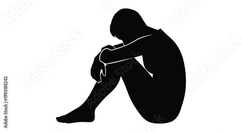 A solitary figure sits with knees drawn up expressing sadness a dark silhouette