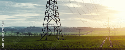Foto Scenic view of electricity pylons stretching across green fields warm sunset sky background