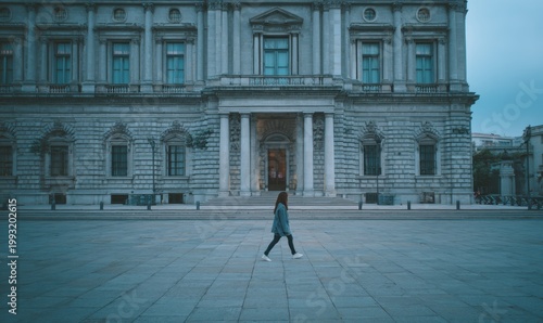 Person crossing paved square before majestic classical building
