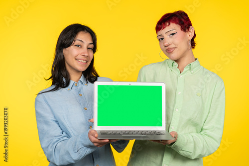 Young women presenting laptop with green screen for copy space