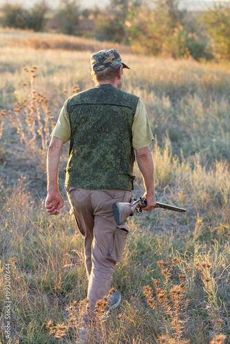 A hunter with a gun in camouflage clothing. A gentleman with a gun, medium shot, unrecognizable.