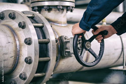 Принти на полотні Industrial worker turning a large valve on a pipeline in a factory setting