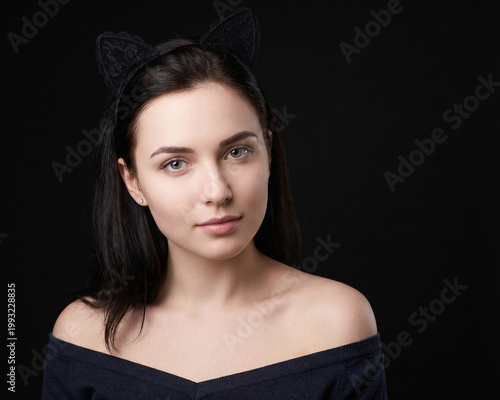 Attractive woman wearing cat ears on black background